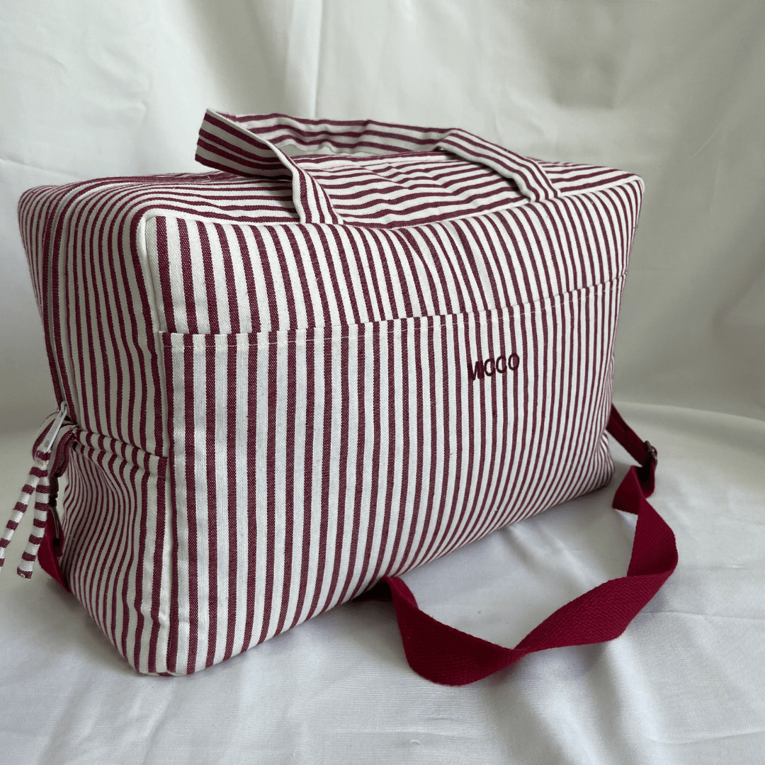 Bolsa de tela rayada con bolsillo frontal e interior, asas de mano y correa larga ajustable, ideal como equipaje de cabina